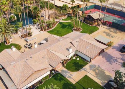 An overhead shot of the Estate House at Rancho de las Palmas wedding venue. Visible are the house itself, a tennis court, a small yard, and a private lagoon