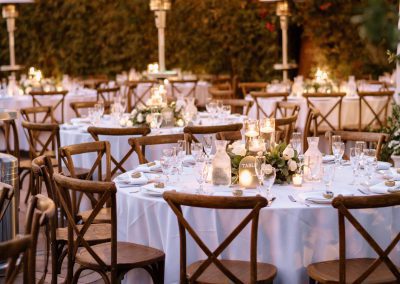 An outdoor wedding reception area with round, white tables and hanging lights